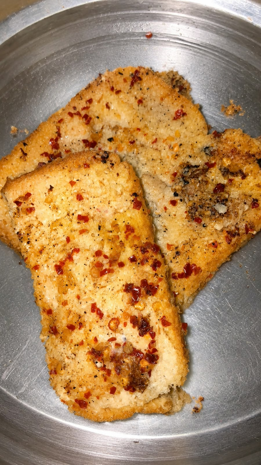 Slices of golden chicken garlic bread topped with chilli flakes